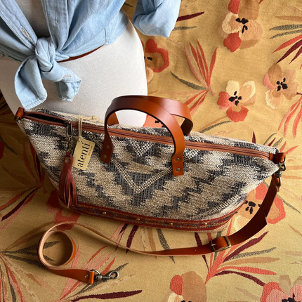 Woven handbag with leather straps on a floral-patterned surface