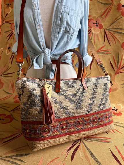Patterned handbag with brown strap and tassel on a floral background