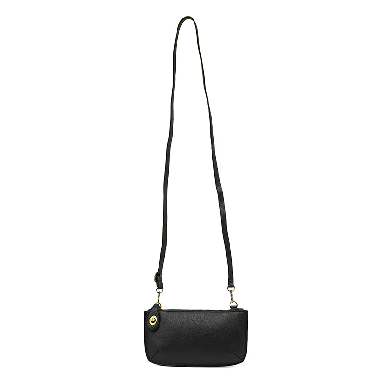 A black-colored mini crossbody wristlet clutch with brass plated hardware and a printed lining, displayed with the full strap visible