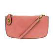 A blush-colored mini crossbody wristlet clutch with brass plated hardware and a printed lining, displayed with the wristlet strap visible
