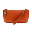 A burnt orange-colored mini crossbody wristlet clutch with brass plated hardware and a printed lining, displayed with the wristlet strap visible