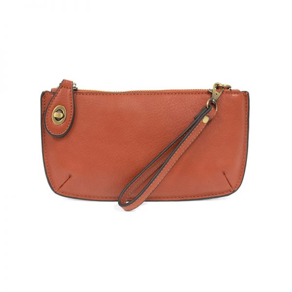 A cinnamon-colored mini crossbody wristlet clutch with brass plated hardware and a printed lining, displayed with the wristlet strap visible