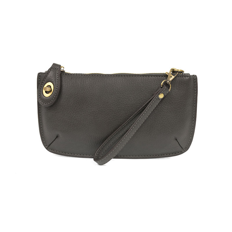 A dark grey-colored mini crossbody wristlet clutch with brass plated hardware and a printed lining, displayed with the wristlet strap visible