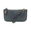 A denim-colored mini crossbody wristlet clutch with brass plated hardware and a printed lining, displayed with the wristlet strap visible