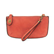 A desert coral-colored mini crossbody wristlet clutch with brass plated hardware and a printed lining, displayed with the wristlet strap visible