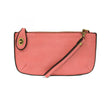A pink-colored mini crossbody wristlet clutch with brass plated hardware and a printed lining, displayed with the wristlet strap visible