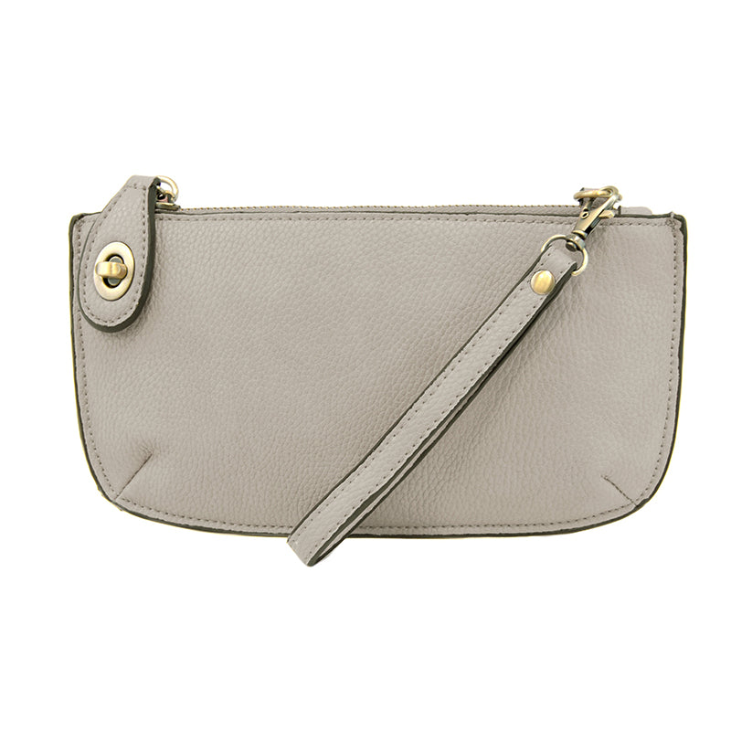 A grey-colored mini crossbody wristlet clutch with brass plated hardware and a printed lining, displayed with the wristlet strap visible