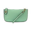 A mint-colored mini crossbody wristlet clutch with brass plated hardware and a printed lining, displayed with the wristlet strap visible