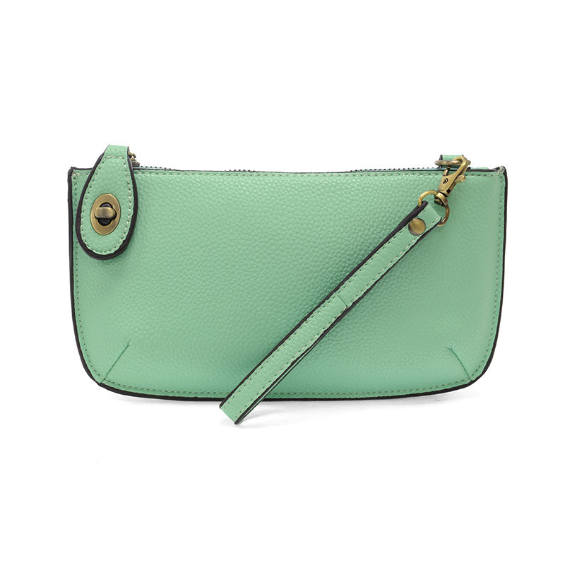 A mint-colored mini crossbody wristlet clutch with brass plated hardware and a printed lining, displayed with the wristlet strap visible