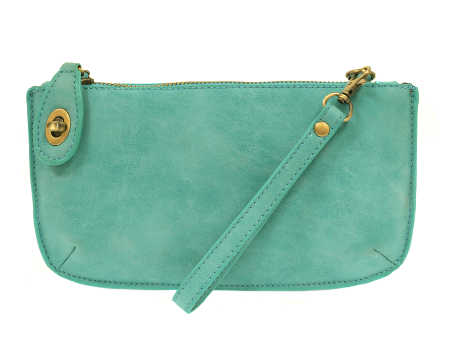 A light turquoise-colored mini crossbody wristlet clutch with brass plated hardware and a printed lining, displayed with the wristlet strap visible