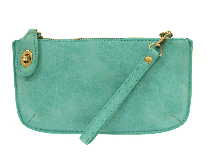 A light turquoise-colored mini crossbody wristlet clutch with brass plated hardware and a printed lining, displayed with the wristlet strap visible