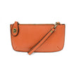 A mango-colored mini crossbody wristlet clutch with brass plated hardware and a printed lining, displayed with the wristlet strap visible