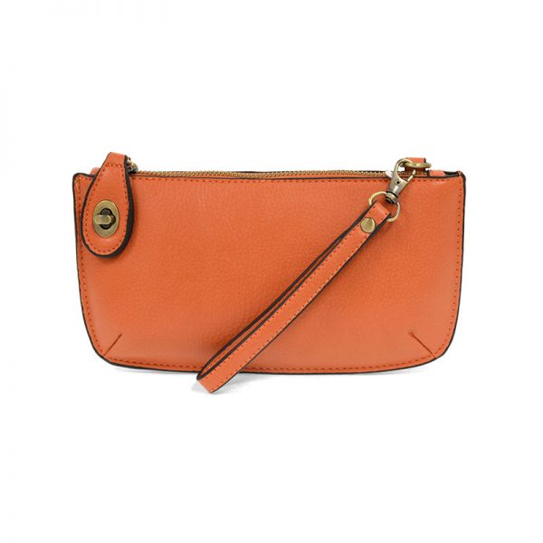 A mango-colored mini crossbody wristlet clutch with brass plated hardware and a printed lining, displayed with the wristlet strap visible