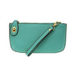A Mayan green-colored mini crossbody wristlet clutch with brass plated hardware and a printed lining, displayed with the wristlet strap visible