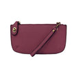 A mulberry-colored mini crossbody wristlet clutch with brass plated hardware and a printed lining, displayed with the wristlet strap visible