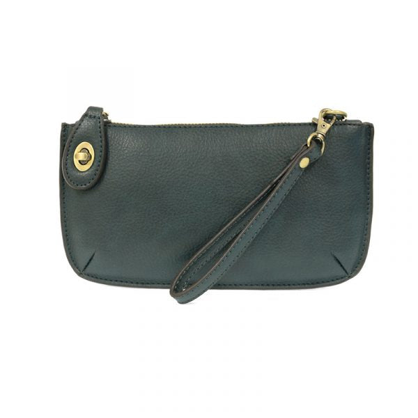 A dark teal-colored mini crossbody wristlet clutch with brass plated hardware and a printed lining, displayed with the wristlet strap visible