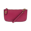 A fuchshia-colored mini crossbody wristlet clutch with brass plated hardware and a printed lining, displayed with the wristlet strap visible