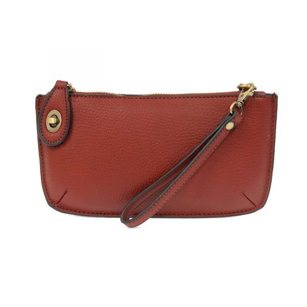 A garnet-colored mini crossbody wristlet clutch with brass plated hardware and a printed lining, displayed with the wristlet strap visible