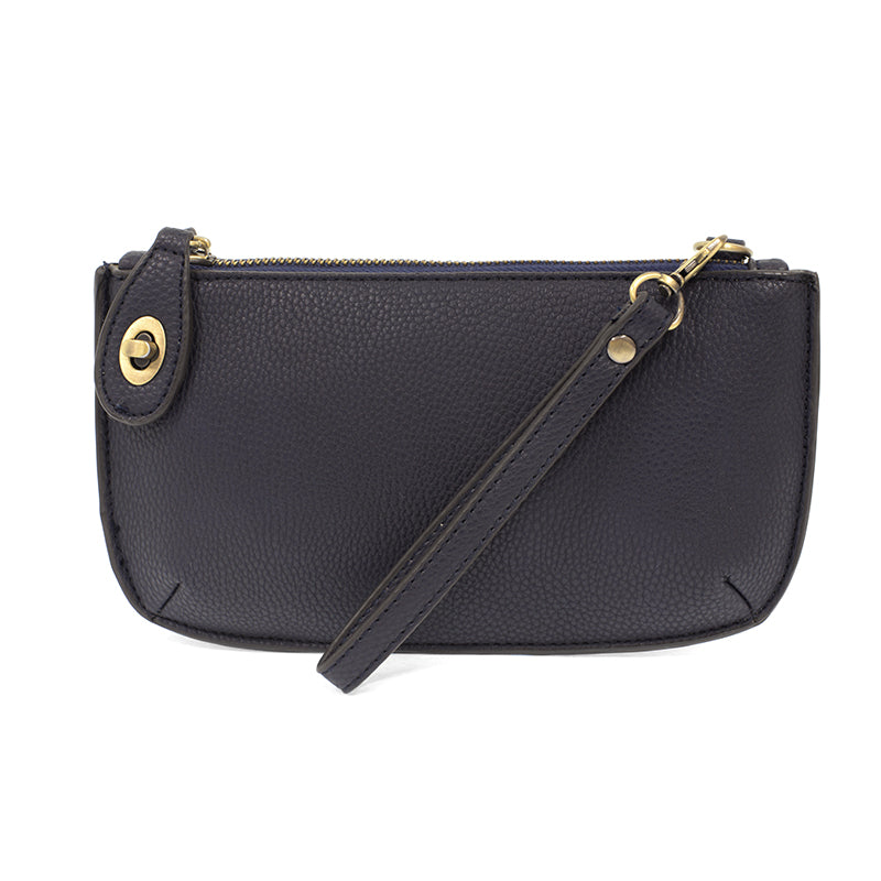 A new navy-colored mini crossbody wristlet clutch with brass plated hardware and a printed lining, displayed with the wristlet strap visible