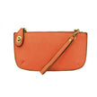 An orange-colored mini crossbody wristlet clutch with brass plated hardware and a printed lining, displayed with the wristlet strap visible