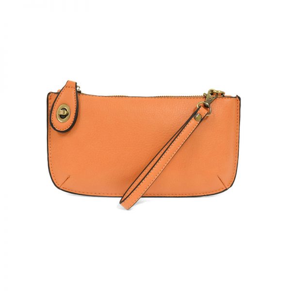An orange sherbert-colored mini crossbody wristlet clutch with brass plated hardware and a printed lining, displayed with the wristlet strap visible