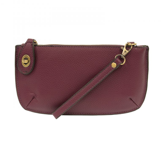 A plum-colored mini crossbody wristlet clutch with brass plated hardware and a printed lining, displayed with the wristlet strap visible