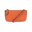 A pumpkin-colored mini crossbody wristlet clutch with brass plated hardware and a printed lining, displayed with the wristlet strap visible