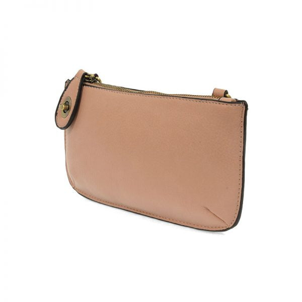 A rose ash-colored mini crossbody wristlet clutch with brass plated hardware and a printed lining, displayed from the back