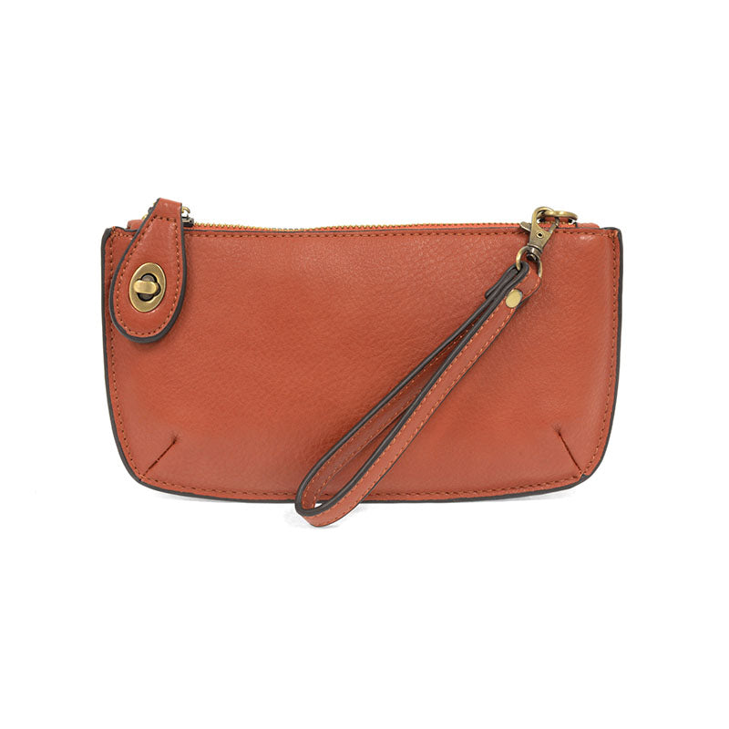 A sangria-colored mini crossbody wristlet clutch with brass plated hardware and a printed lining, displayed with the wristlet strap visible