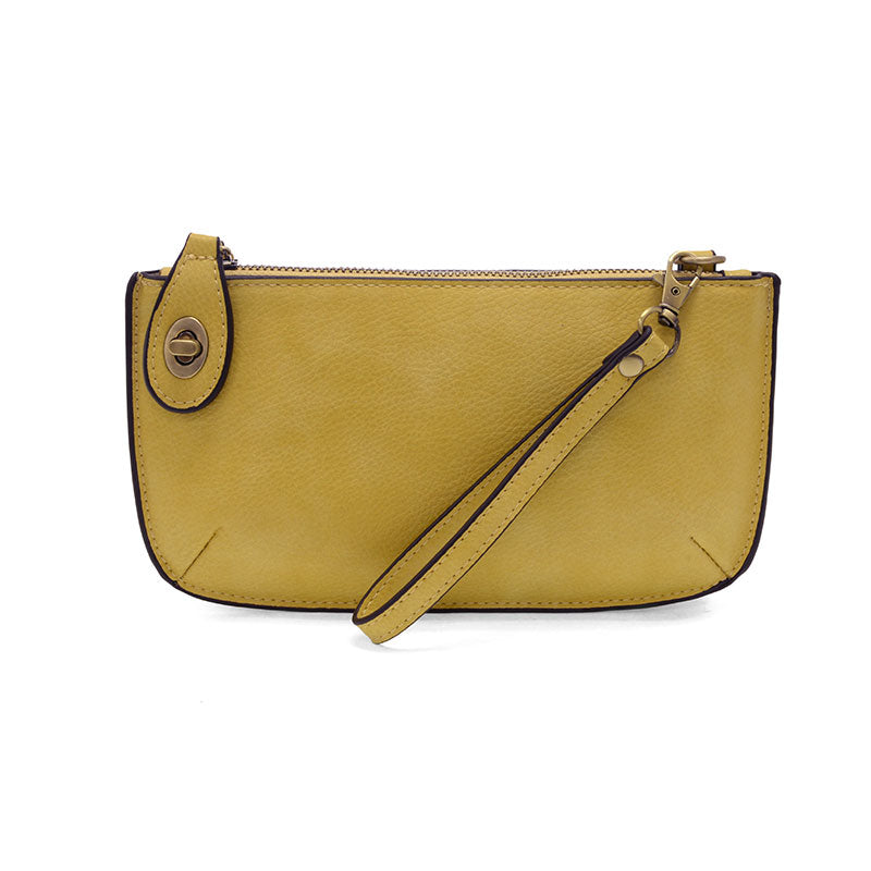 A shortbread yellow-colored mini crossbody wristlet clutch with brass plated hardware and a printed lining, displayed with the wristlet strap visible