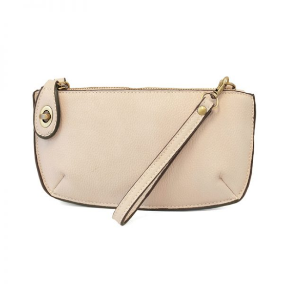 A stone-colored mini crossbody wristlet clutch with brass plated hardware and a printed lining, displayed with the wristlet strap visible