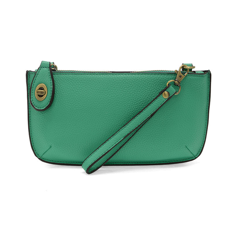 A summer green-colored mini crossbody wristlet clutch with brass plated hardware and a printed lining, displayed with the wristlet strap visible