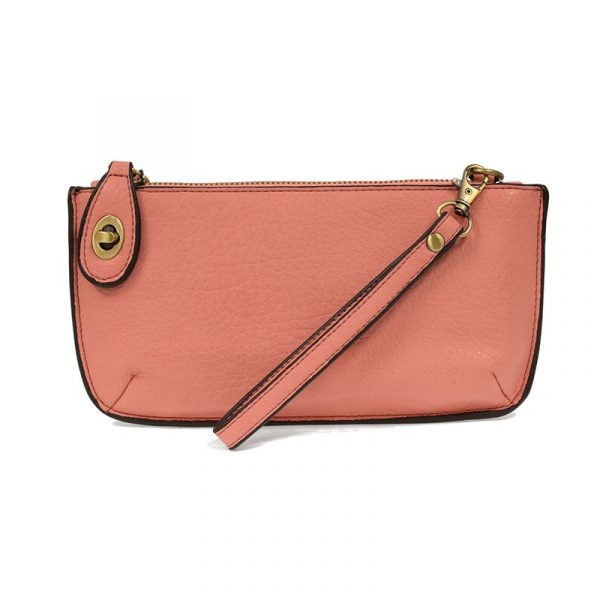 A taffy pink-colored mini crossbody wristlet clutch with brass plated hardware and a printed lining, displayed with the wristlet strap visible