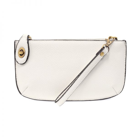 A white-colored mini crossbody wristlet clutch with brass plated hardware and a printed lining, displayed with the wristlet strap visible