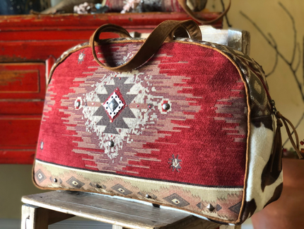 Red patterned bag with leather handle on a wooden surface