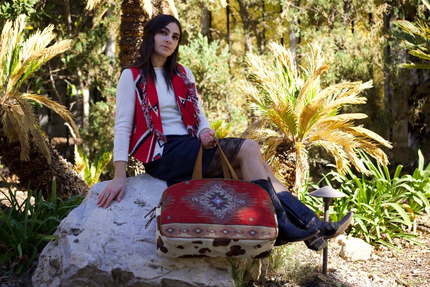 Woman sitting on a rock with a patterned suitcase in a forest setting