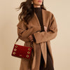 Woman wearing a brown coat holding a bag 